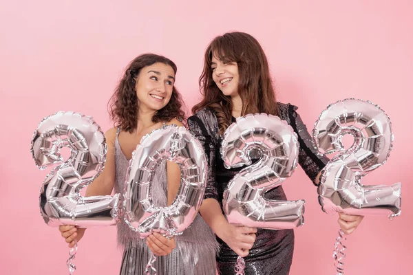 Deux filles heureuses avec des ballons en feuille d'argent sous la forme des numéros 2022. — Photo