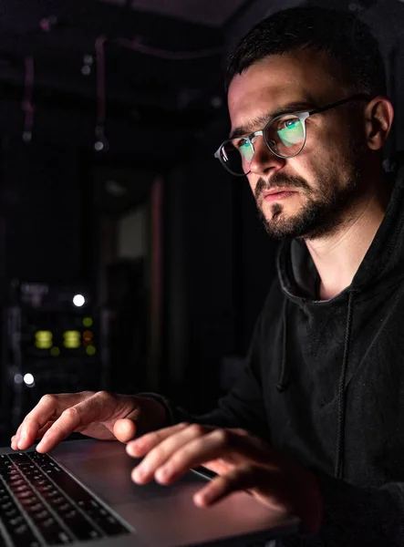 Un hombre con gafas trabaja en una computadora tarde en la noche. — Foto de Stock