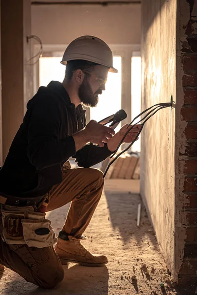 Arbejderen skærer ledninger med linemans tang. - Stock-foto