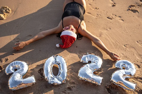 Chica con globos de plata en forma de números para el próximo año cerca del mar — Foto de Stock