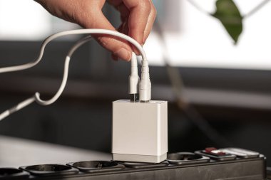 Odanın bulanık arka planında cihazlar için beyaz USB şarj ediliyor, yakın plan..