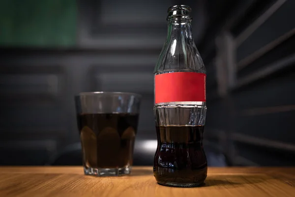 Close-up de uma garrafa de vidro com um rótulo vermelho e um copo de bebida carbonatada. — Fotografia de Stock