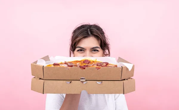 Çekici kız pembe arka planda karton bir kutuda pizza tutuyor.. — Stok fotoğraf