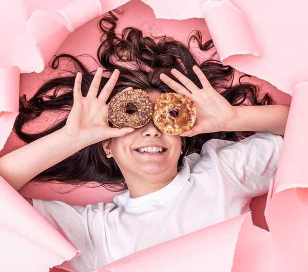 Kağıt pembe arka planda parlak donutları olan neşeli kız.. — Stok fotoğraf
