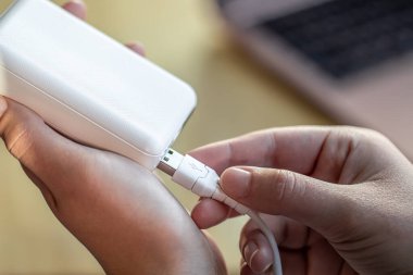 Beyaz USB kablo ve beyaz güç bankasını tutan kadınlar..