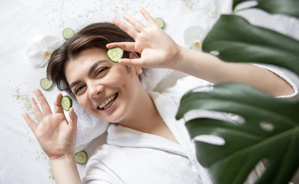 Glückliche junge Frau in einem Wellness-Salon mit Gurken auf den Augen, Draufsicht. — Stockfoto
