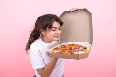Pembe arka planda açık bir pizza kutusu olan çekici bir kız..