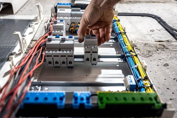 Un électricien masculin travaille dans un standard avec un câble de connexion électrique . — Photo
