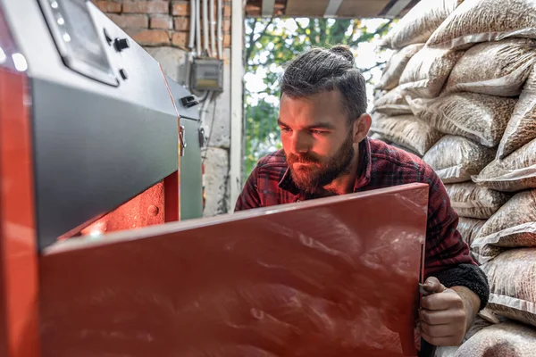 A man looking into a boiler on solid fuel, open door boiler with flames of fire. — Stock Photo, Image