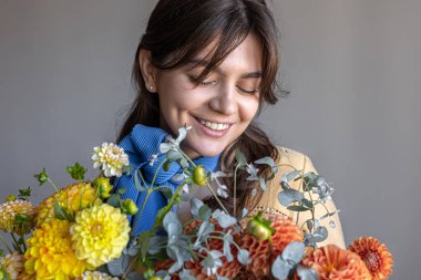 Genç bir kadın bir buket kasımpatı çiçeği tutuyor..