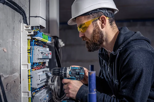 Un électricien masculin travaille dans un standard avec un câble de connexion électrique . — Photo