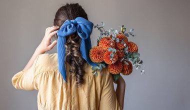 Genç bir kadın elinde bir buket kasımpatı çiçeği tutuyor..