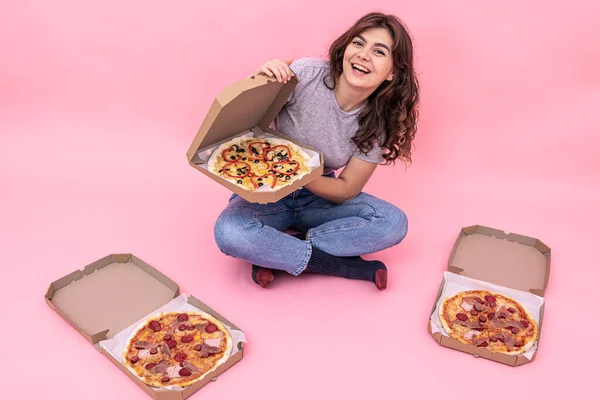 분홍색 배경으로 피자를 배달하기 위해 상자에서 피자를 꺼내는 매혹적 인 소녀. — 스톡 사진