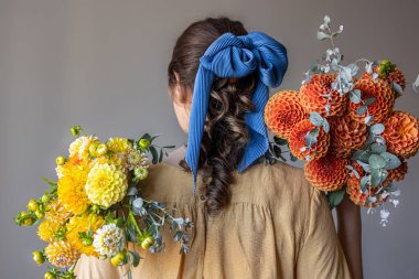 Genç bir kadın bir buket kasımpatı çiçeği tutuyor..