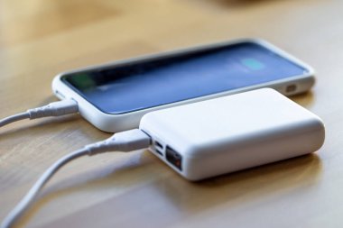 Akıllı telefon küçük beyaz bir enerji bankasından şarj edilir..