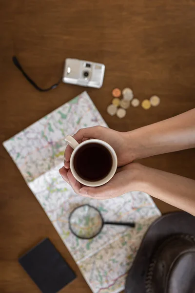 Lapos fektetés, térkép, nagyító, dokumentumok és egy csésze kávé egy nő kezében. — Stock Fotó