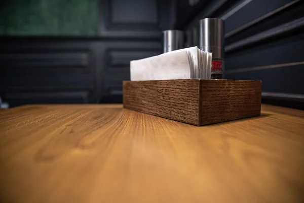 Деревянная коробка со специями и салфетками на столе в кафе. — стоковое фото
