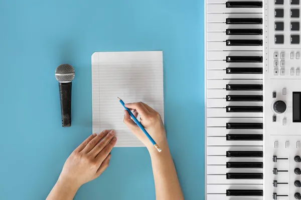 Teclas musicais, microfone e papel em branco sobre fundo azul. — Fotografia de Stock