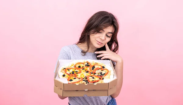 분홍색 배경으로 배달하려고 상자 안에 피자를 넣은 매혹적 인 소녀. — 스톡 사진