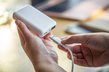 Beyaz USB kablo ve beyaz güç bankasını tutan kadınlar..