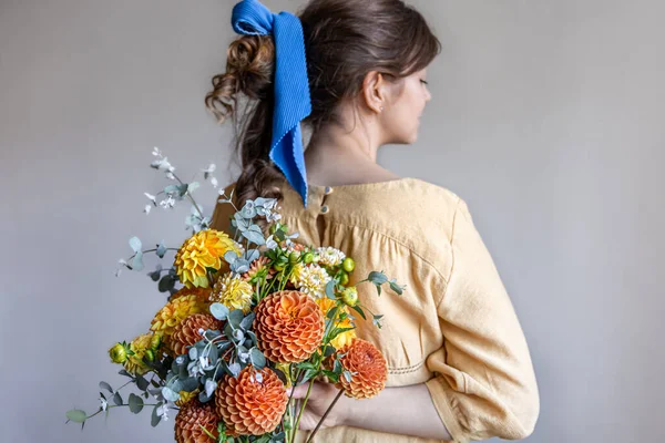 若い女性は背中の後ろに菊の花束を持っています. — ストック写真