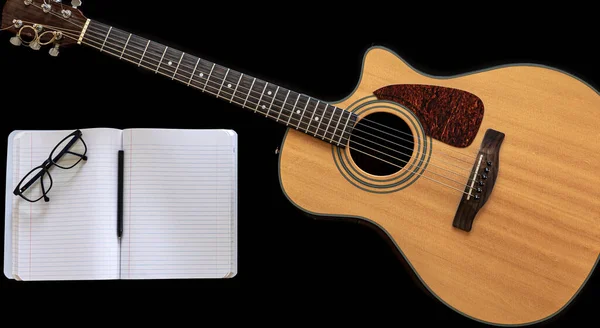 Klasyczna gitara akustyczna i otwarty notatnik na czarnym tle. — Zdjęcie stockowe