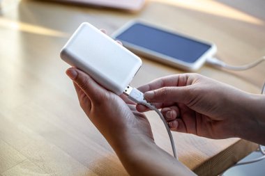 Beyaz USB kablo ve beyaz güç bankasını tutan kadınlar..