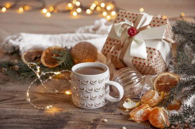 Bulanık bir arka planda şenlik bardağı ve mandalinalı Noel kompozisyonu.