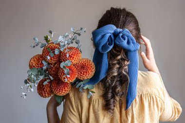 Genç bir kadın elinde bir buket kasımpatı çiçeği tutuyor..