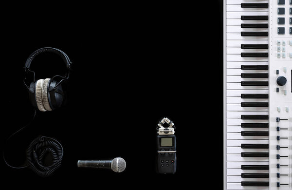 Music keys, headphones, recorder and microphone on a black background, flat lay.