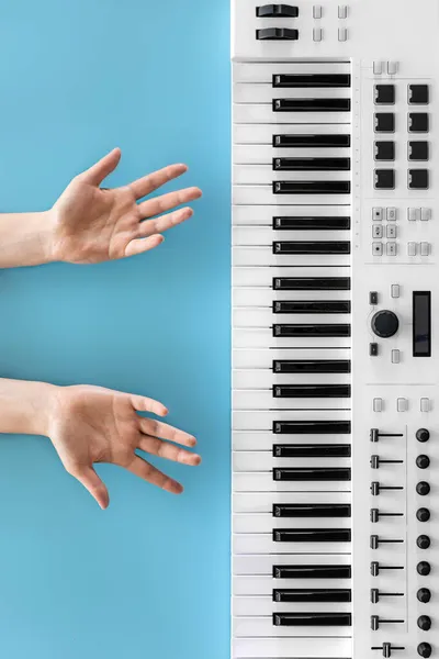 Female hands and musical keys on a blue background, top view. — Stock Photo, Image