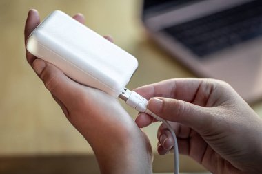 Beyaz USB kablo ve beyaz güç bankasını tutan kadınlar..
