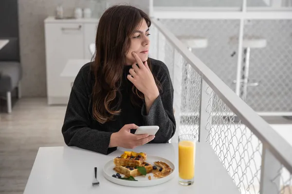 Una mujer está desayunando con gofres belgas y zumo de naranja. — Foto de Stock