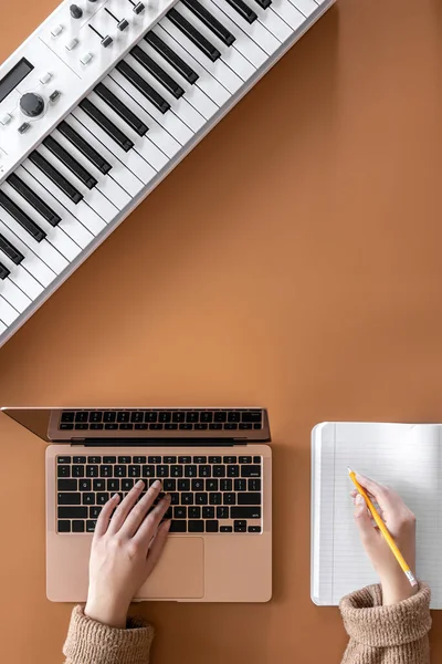 Una mujer trabaja en un ordenador portátil, escribe música, crea una canción, una cama plana. — Foto de Stock