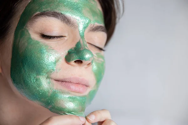 Atrakcyjna młoda kobieta w zielonej masce kosmetycznej na twarzy, przestrzeń do kopiowania. — Zdjęcie stockowe