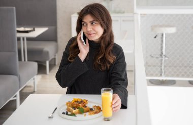 Bir kadın Belçika waffle 'ı ve portakal suyuyla kahvaltı yapıyor..