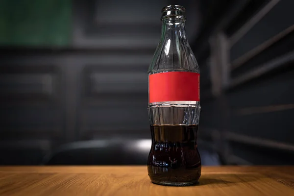 Close-up de uma garrafa de vidro com um rótulo vermelho de bebida carbonatada. — Fotografia de Stock