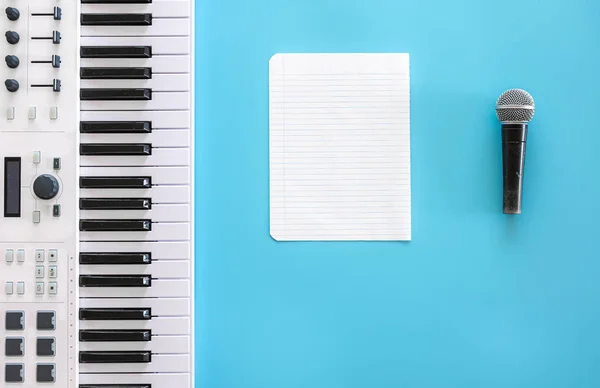 Teclas musicais, microfone e papel em branco sobre fundo azul. — Fotografia de Stock