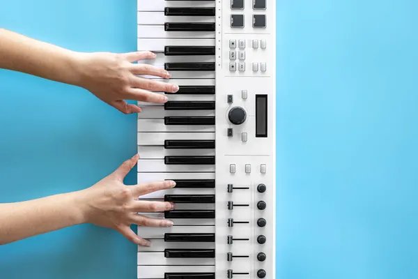 Vrouwelijke handen spelen muzikale toetsen op een blauwe achtergrond, bovenaanzicht. — Stockfoto