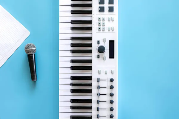 Teclas musicais e uma folha de papel em branco sobre um fundo azul. — Fotografia de Stock