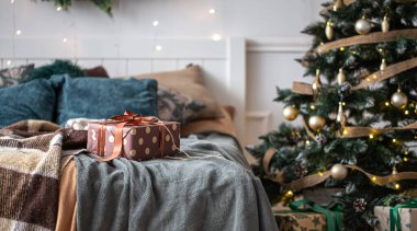 İçinde Noel ağacı ve yatağında hediye kutusu olan rahat bir oda..