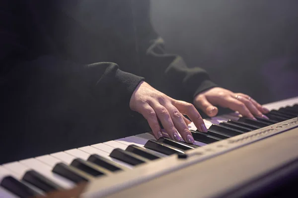 Kvinnliga händer spelar piano nycklar i ett mörkt, dimmigt rum. — Stockfoto