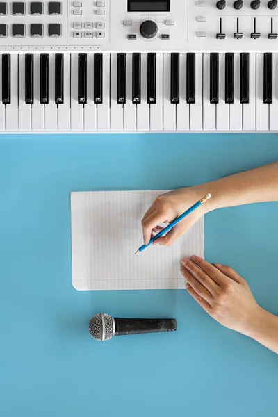 Klucze muzyczne, mikrofon i pusty papier na niebieskim tle. — Zdjęcie stockowe