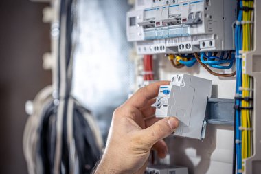 Bir erkek elektrikçi elektrik kablosuyla santralde çalışıyor..