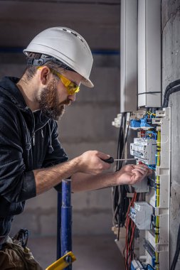 Bir erkek elektrikçi elektrik kablosuyla santralde çalışıyor..