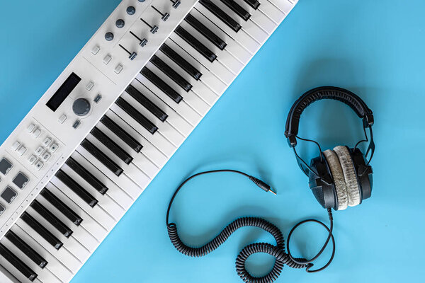 Headphones and keys on a blue background, top view, music hobby concept.