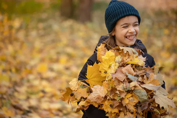Engraçado menina segurando um monte de folhas de outono na floresta. — Fotografia de Stock