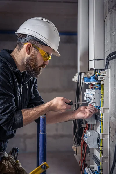 Een mannelijke elektricien werkt in een schakelbord met een elektrische aansluitkabel. — Stockfoto