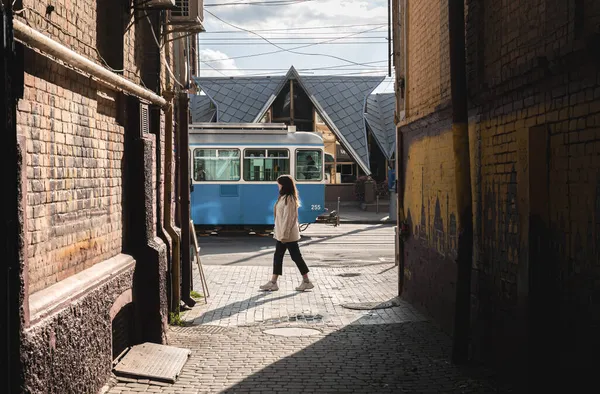 O femeie merge pe stradă pe fundalul unui tramvai în trecere. — Fotografie, imagine de stoc