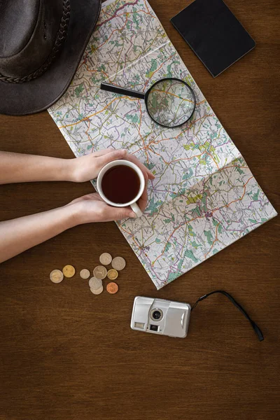 Byt ležel, mapa, lupa, dokumenty a šálek kávy v rukou ženy. — Stock fotografie